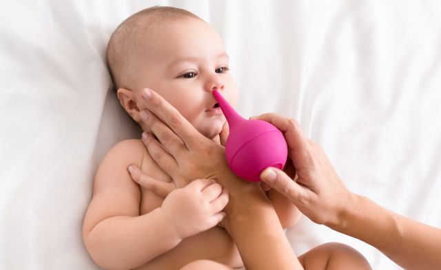 Mama czyści nos noworodkowi za pomocą aspiratora