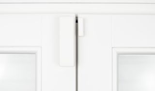 Czujnik otwarcia drzwi zamontowany na białych drzwiach