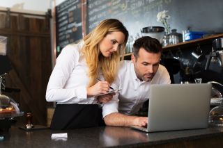 Kobieta i mężczyzna pracujący na laptopie w restauracji