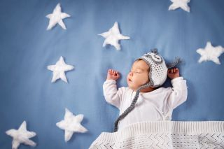 Śpiące dziecko otoczone gwiazdkami z białej waty