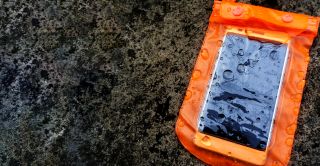 Pomarańczowe mokre wodoszczelne etui ze smartfonem w środku
