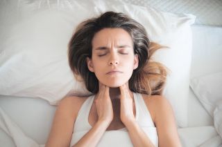 Kobieta leżąca na łóżku z bólem szyi