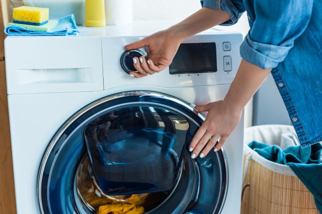 Kobieta wybiera program prania w pralce z funkcją AddWash