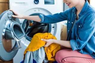 Młoda kobieta wyciąga pranie z białej pralki z funkcją AddWash