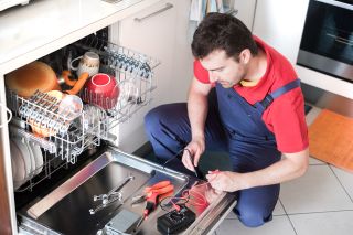 Mechanik naprawia zmywarkę w kuchni