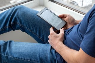 Mężczyzna trzyma na kolanach czytnik e-booków