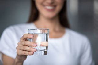 Uśmiechnięta kobieta trzyma szklanę czystej wody