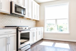 Wnęrze białej kuchni z mikrofalówką podwieszaną