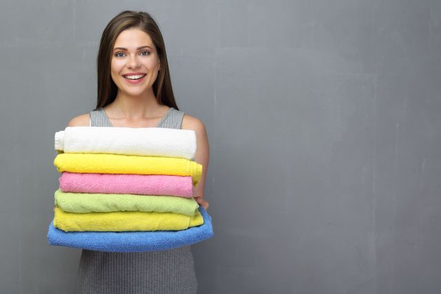 Młoda kobieta trzyma wyprasowane, świeże ręczniki 