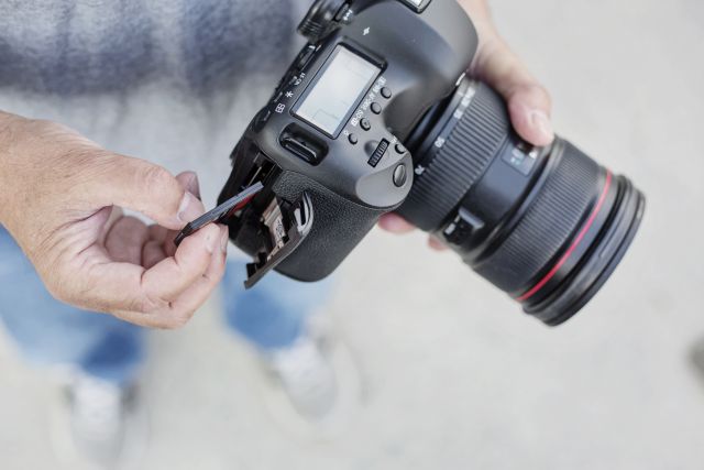 Fotograf wkłada kartę CompactFlash do aparatu