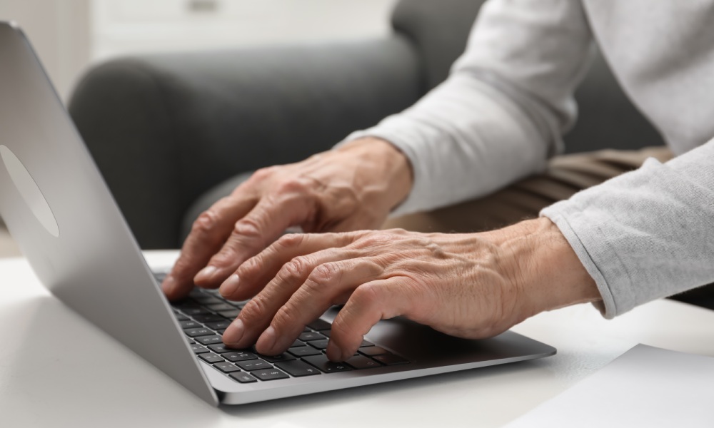 starszy mężczyzna piszący na laptopie