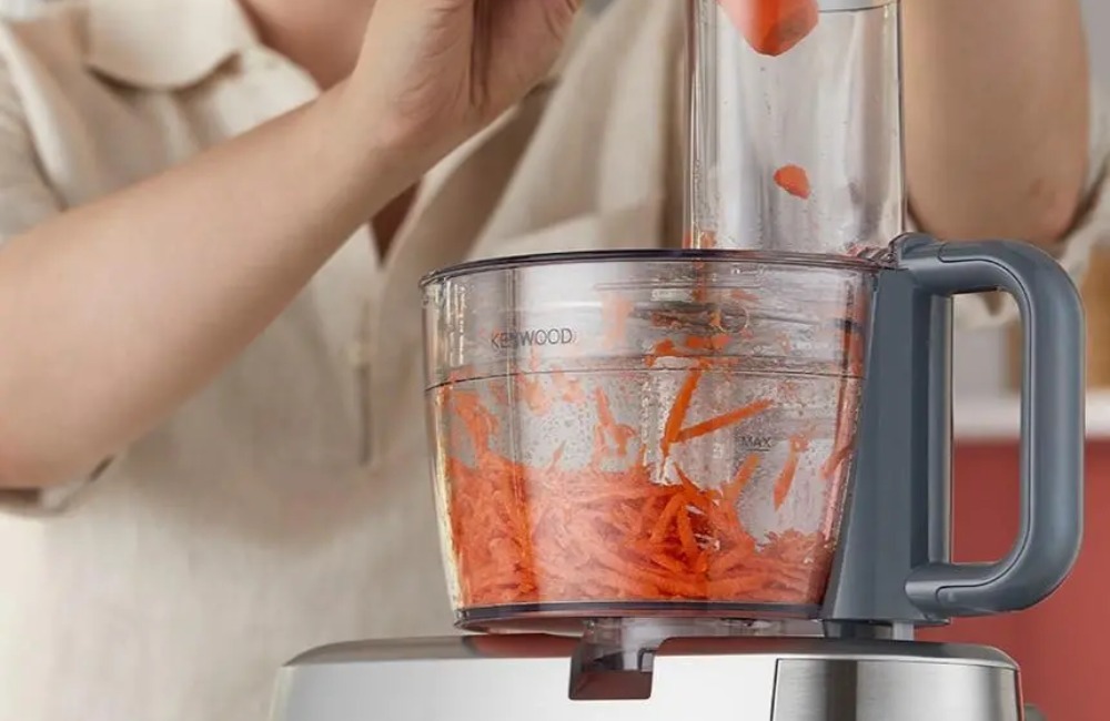 malakser jako część robota kuchennego - kobieta szatkuje marchew