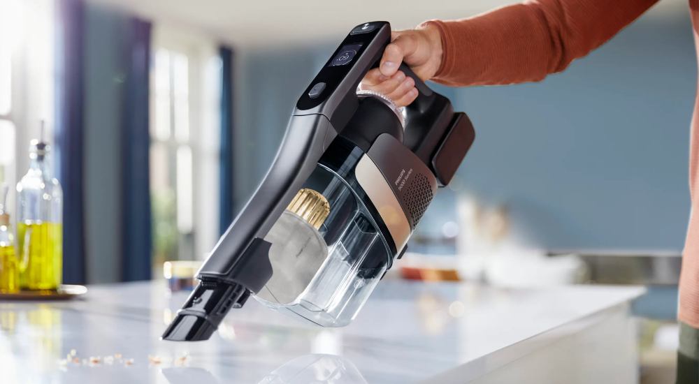 Odkurzanie okruszków z blatu małym ręcznym odkurzaczem bezprzewodowym.