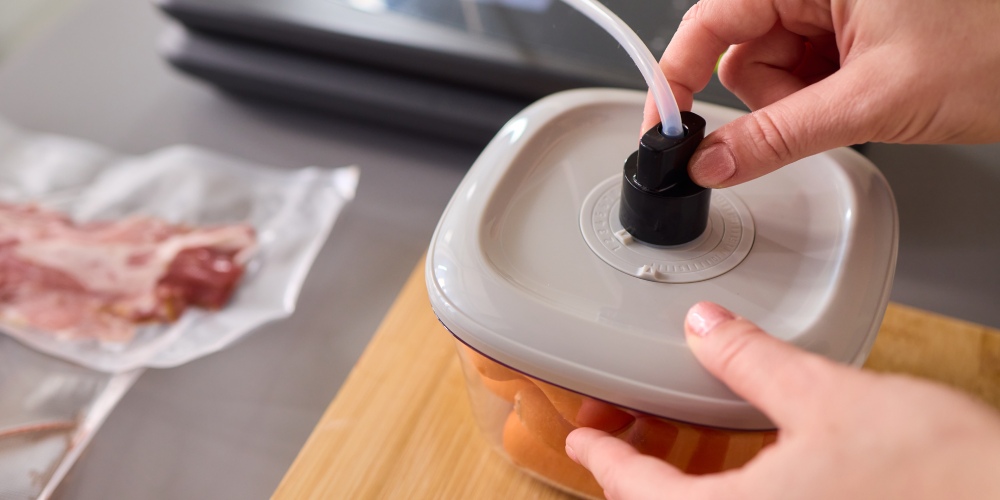 kobieta pakuje żywność do pudełka techniką pakowania pr&oacute;żniowego