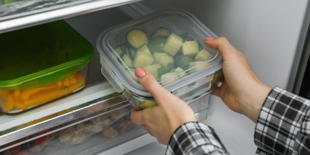 kobieta wstawia do zamrażarki pudełka z jedzeniem