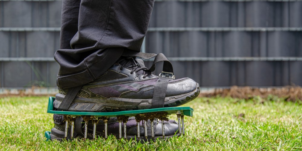 Mężczyzna napowietrzający ziemię nakładkami na buty z kolcami