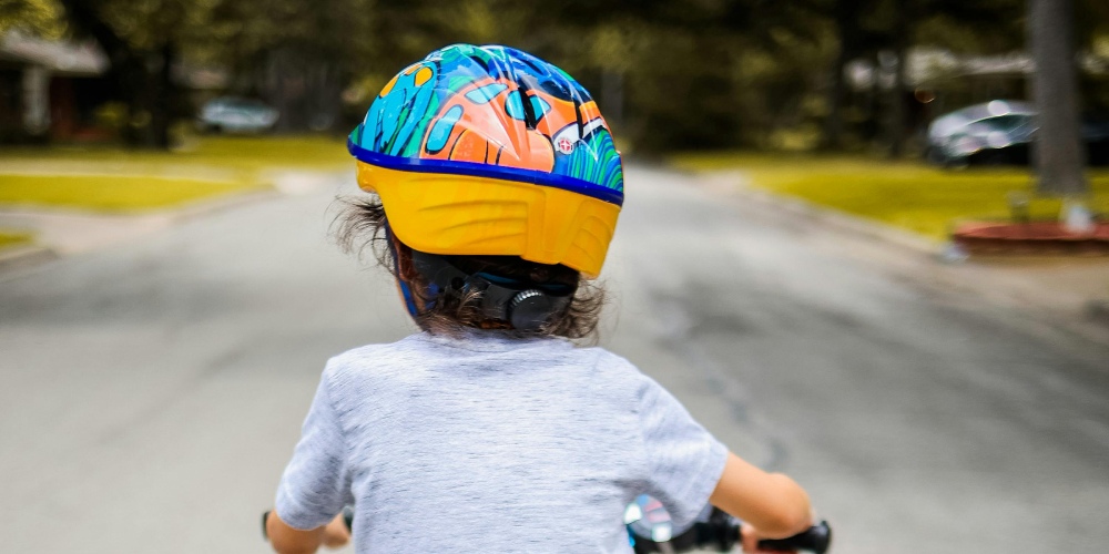 od ilu lat można jeździć na hulajnodze elektrycznej - dziecko w kasku widziane od tyłu