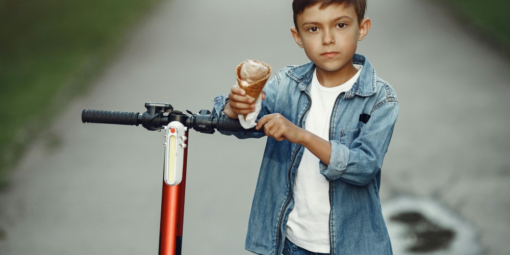 od ilu lat można jeździć na hulajnodze elektrycznej - dziecko stoi przy hulajnodze