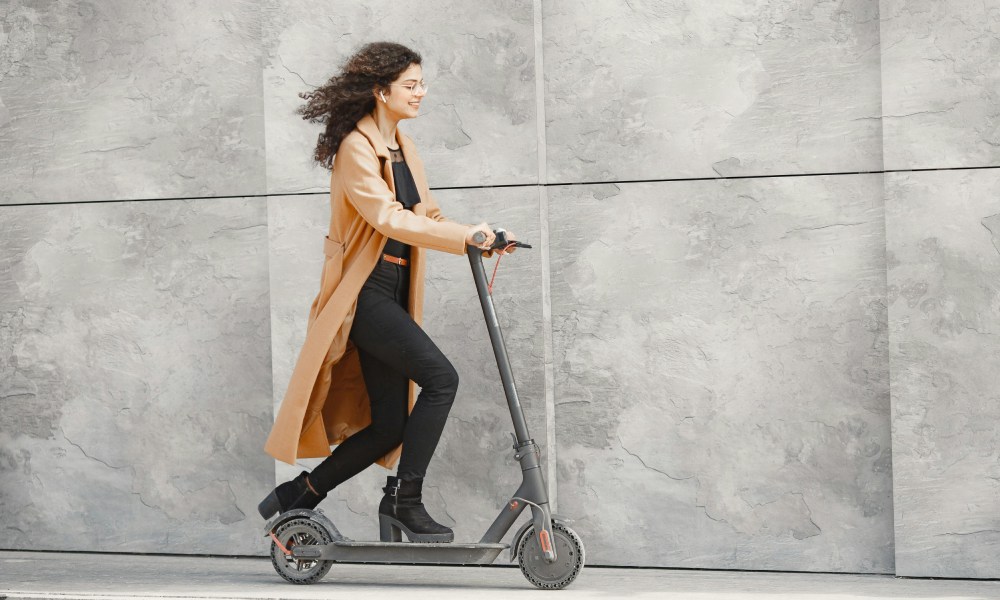od ilu lat można jeździć na hulajnodze elektrycznej - dziewczyna jedzie po chodniku