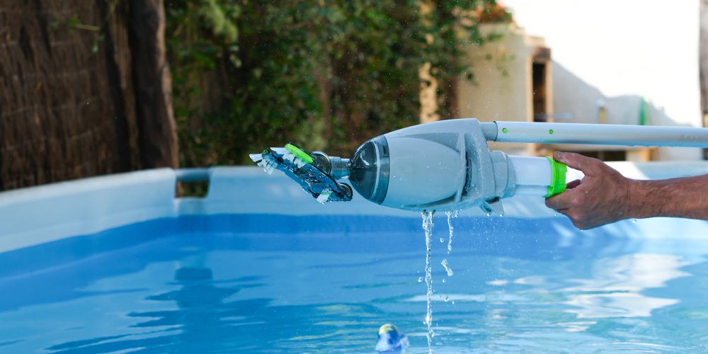 mężczyzna czyści basen odkurzaczem ręcznym do basenu