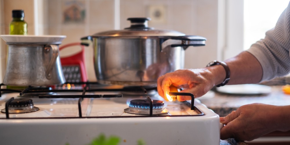 kobieta przkręcająca płomień na płycie gazowej
