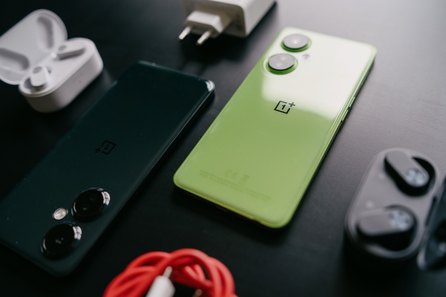 dwa smartfony OnePlus Nord CE3 Lite 5G leżą na czarnym stole w otoczeniu akcesori&oacute;w