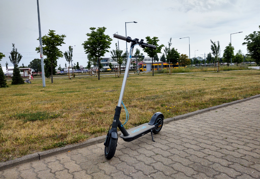 hulajnoga motus scooty 10 lite 2022 stoi dziarsko na chodniku i pozuje do zdjęcia