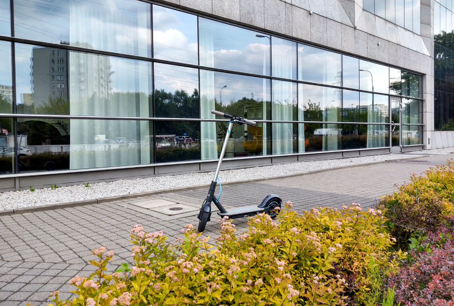 hulajnoga elektryczna motus scooty 10 lite 2022 na tle nowoczesnego biurowca
