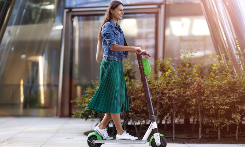 Kobieta podczas jazdy na hulajnodze elektrycznej w mieście.