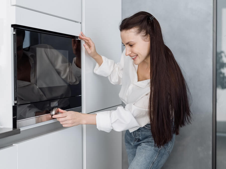 Młoda kobieta wybiera program w piekarniku elektrycznym do zabudowy