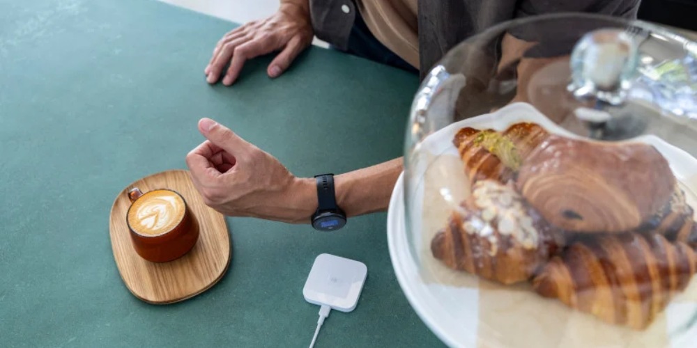 Mężczyzna płaci za zakupy w kawiarni zegarkiem z funkcją Garmin Pay