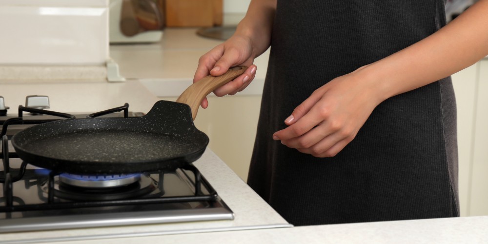 Kobieta grzejąca patelnię na płycie gazowej