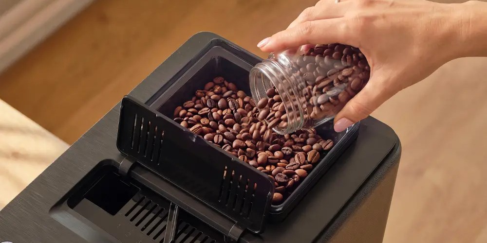 kobieta wsypuje ziarna kawy do ekspresu Sencor ENZE