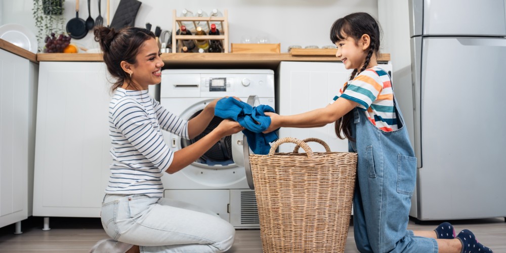 Kobieta i dziewczynka wyciągające pranie z pralki