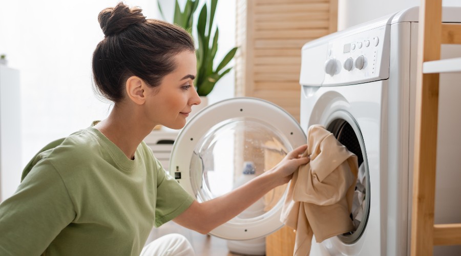 kobieta ładująca pranie do pralki