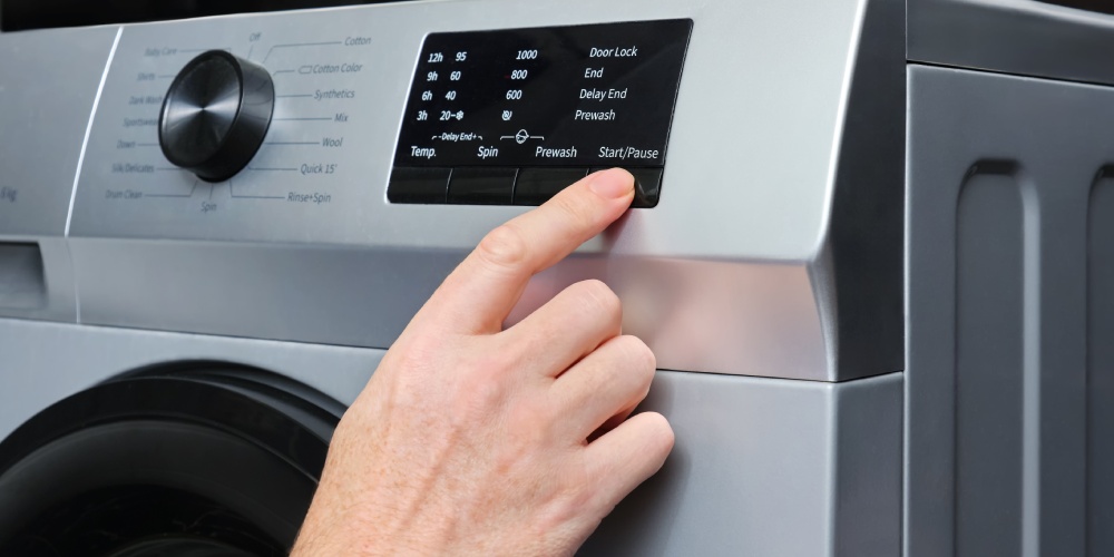 mężczyzna przyciska palcem panel sterowania w pralce