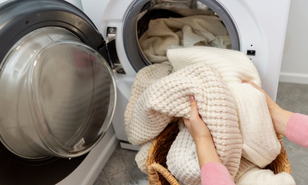 kobieta wkłada wełniane swetry do pralki