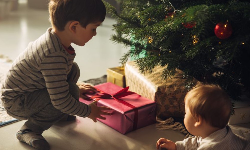 dziecko wyjmuje prezent spod choinki