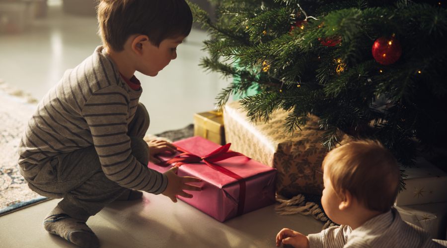 Dwójka dzieci wyciągających prezenty spod choinki