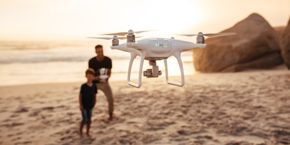 tata z synem puszczają drona na plaży