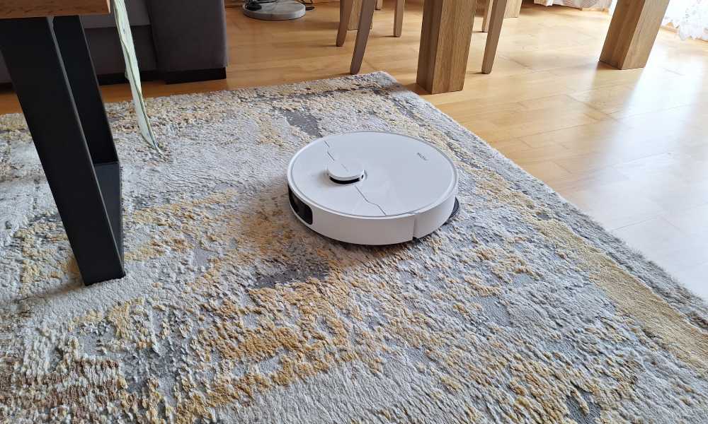 Robot Mova e40 podczas odkurzania dywanu w salonie.