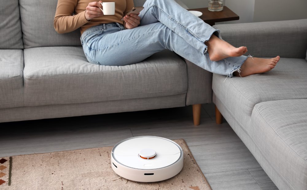 kobieta odpoczywa w salonie, a robot automatyczny sprząta