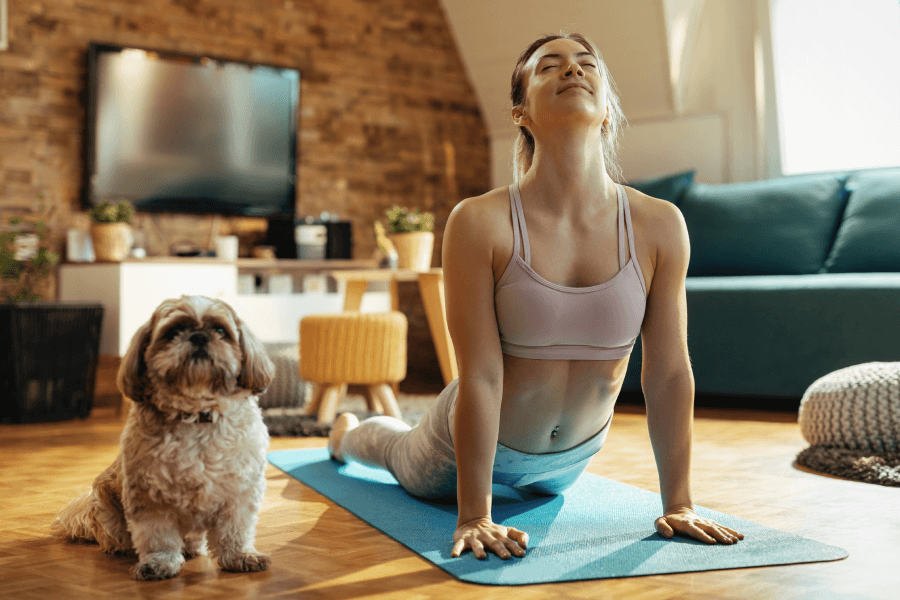 Kobieta ćwiczy w domu obok siedzi pies