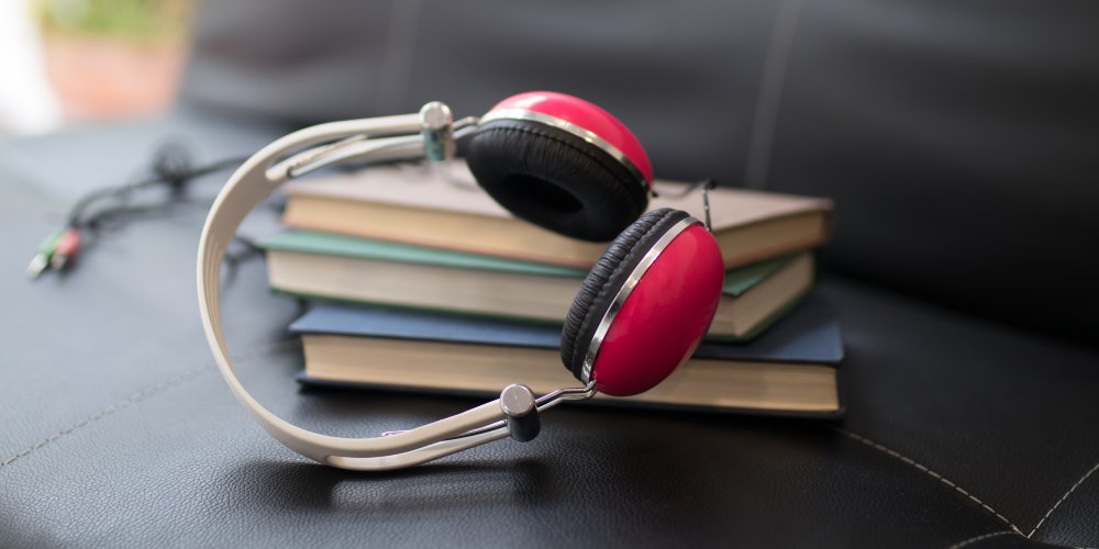 Przewodowe słuchawki nauszne dla audiofil&oacute;w leżą na stole obok książek.