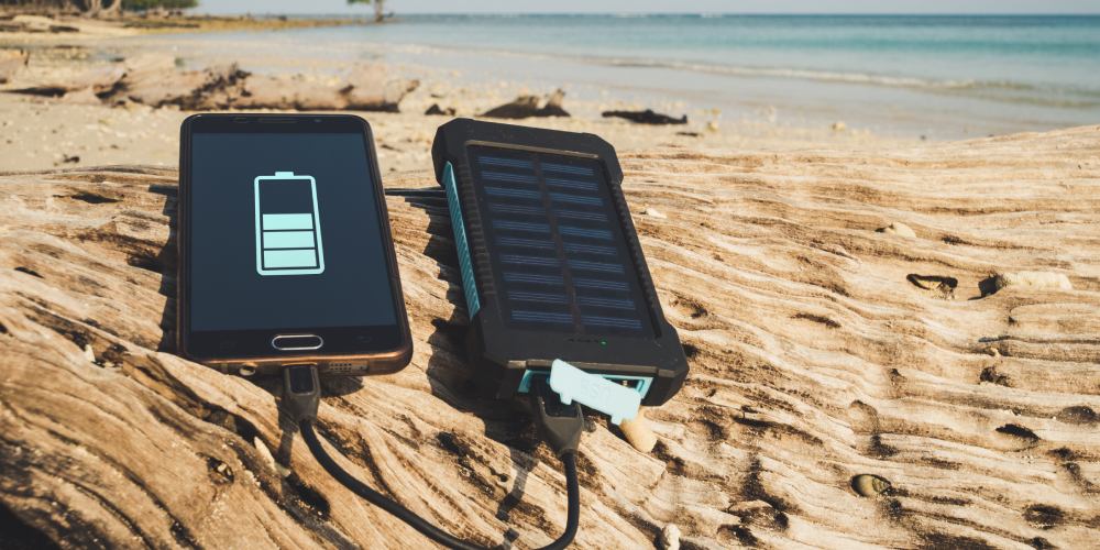 telefon ładujący się przez solarny powerbank na piasku na plaży