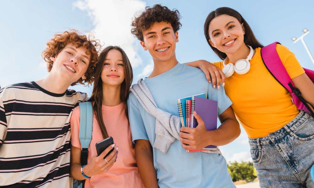 Grupa nastoletnich uczniów z gadżetami i akcesoriami szkolnymi.