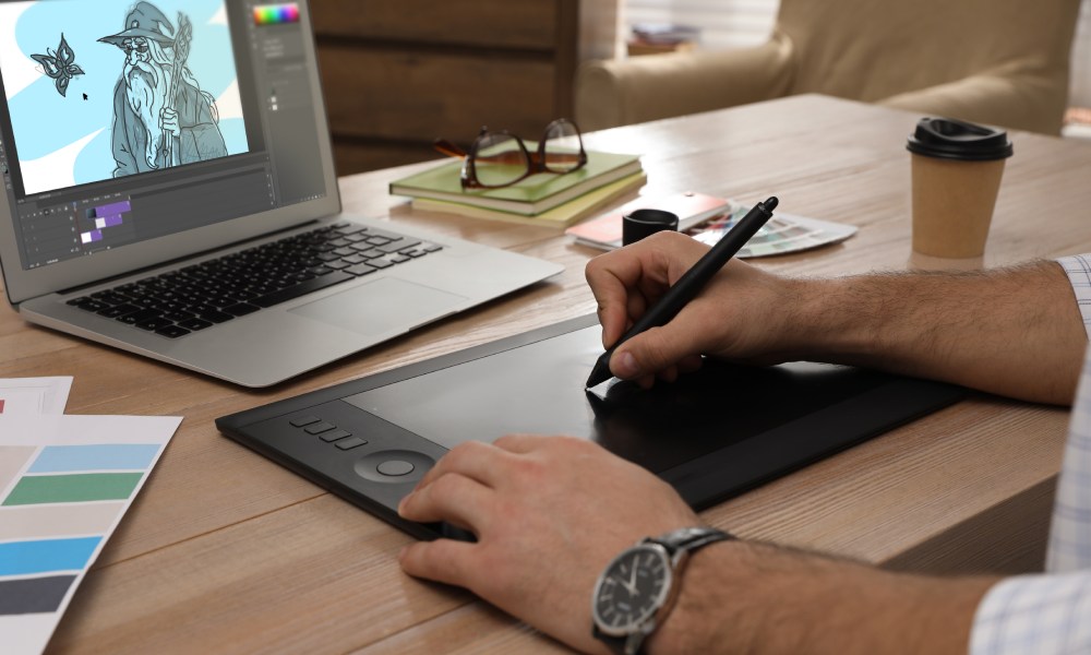 rysownik trzymający w dłoni rysik i korzystający z tabletu graficznego
