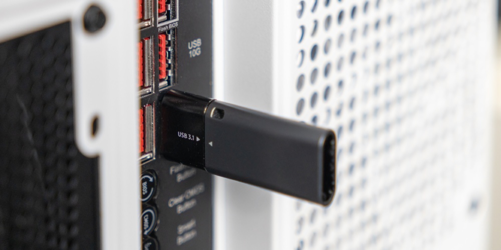 szary pendrive wpięty w biały komputer