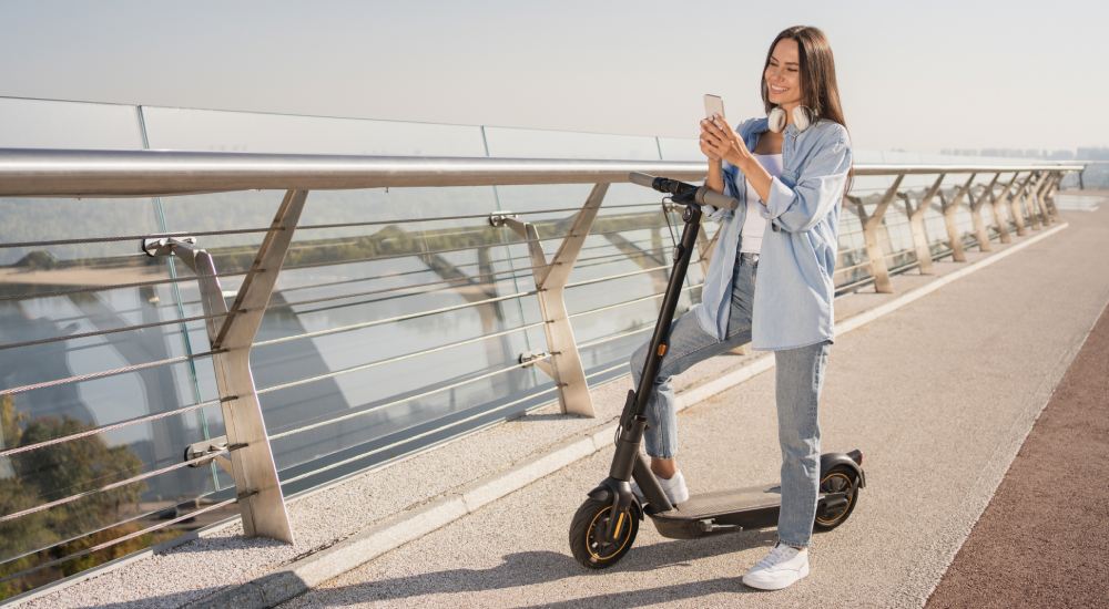 Zadowolona kobieta podczas przejażdżki własną hulajnogą elektryczną.
