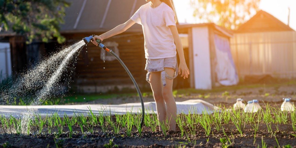 Dziewczynka podlewająca ogr&oacute;d